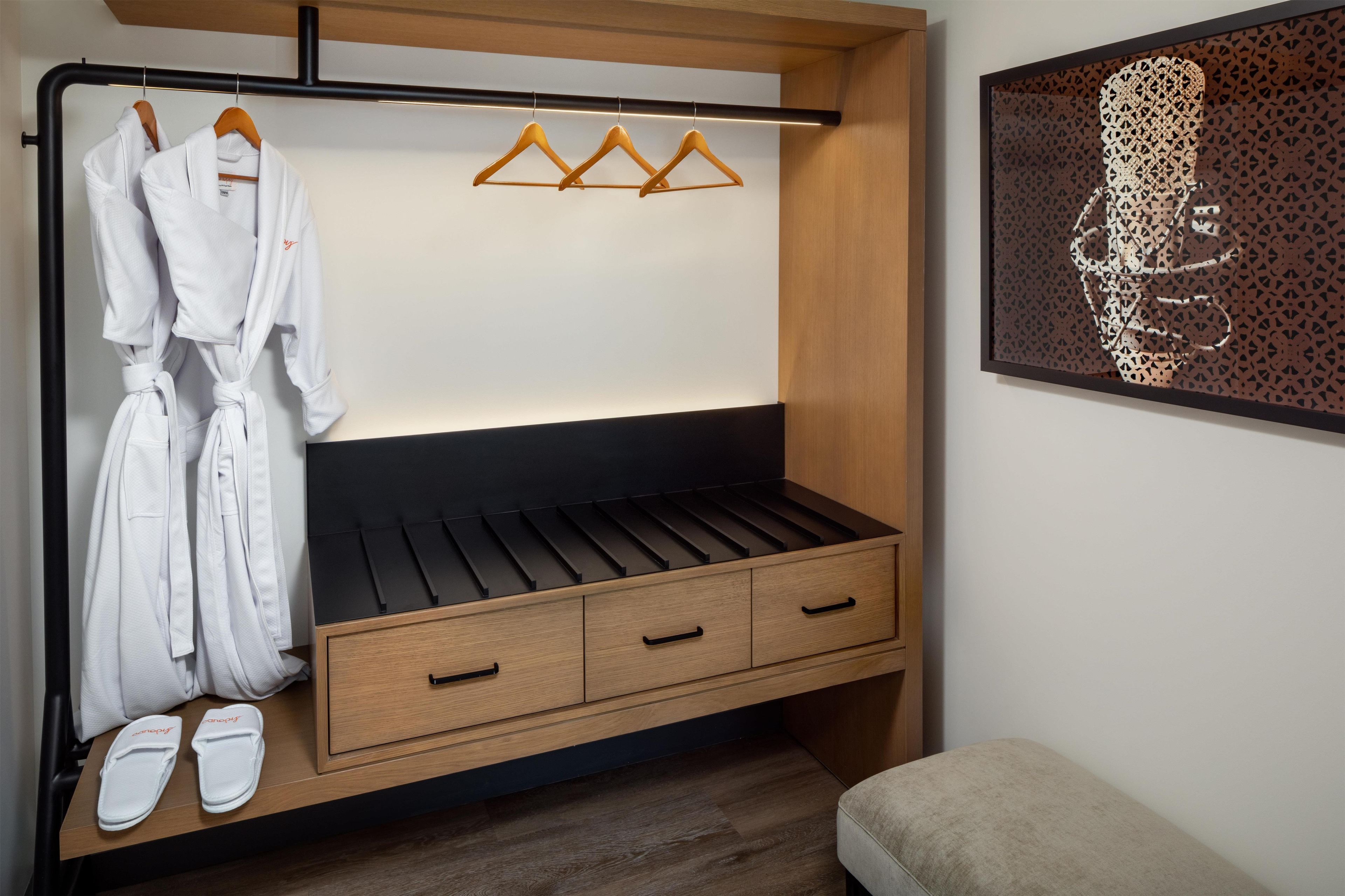 A bedroom with a bed, a wooden wardrobe, a robe, and slippers.
