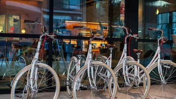Bicicletas estacionadas em frente a um edifício com grandes janelas.