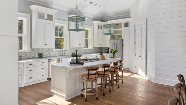 A spacious kitchen with a large island, wooden bar stools, white cabinetry, and pendant lighting. - 5BR 5BA Luxury Home with Private Pool on IOP! (Isle of Palms)