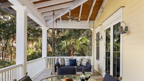 A covered porch with a glass table, a sofa, and a view of the outdoors. - 5BR 5BA Luxury Home with Private Pool on IOP! (Isle of Palms)