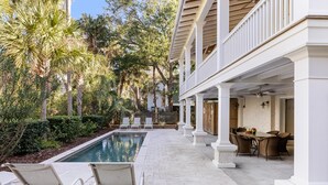 A poolside area with lounge chairs, a dining table, and a covered patio. - 5BR 5BA Luxury Home with Private Pool on IOP! (Isle of Palms)