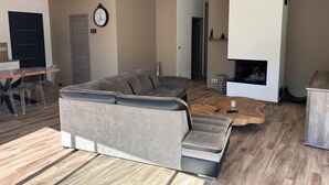 En moderne stue med en hjørnesofa, et træbord og en pejs.