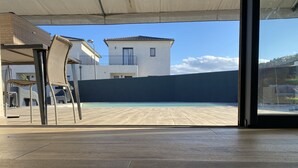 Udsigt til en swimmingpool fra en overdækket patio med en stol og et bord.