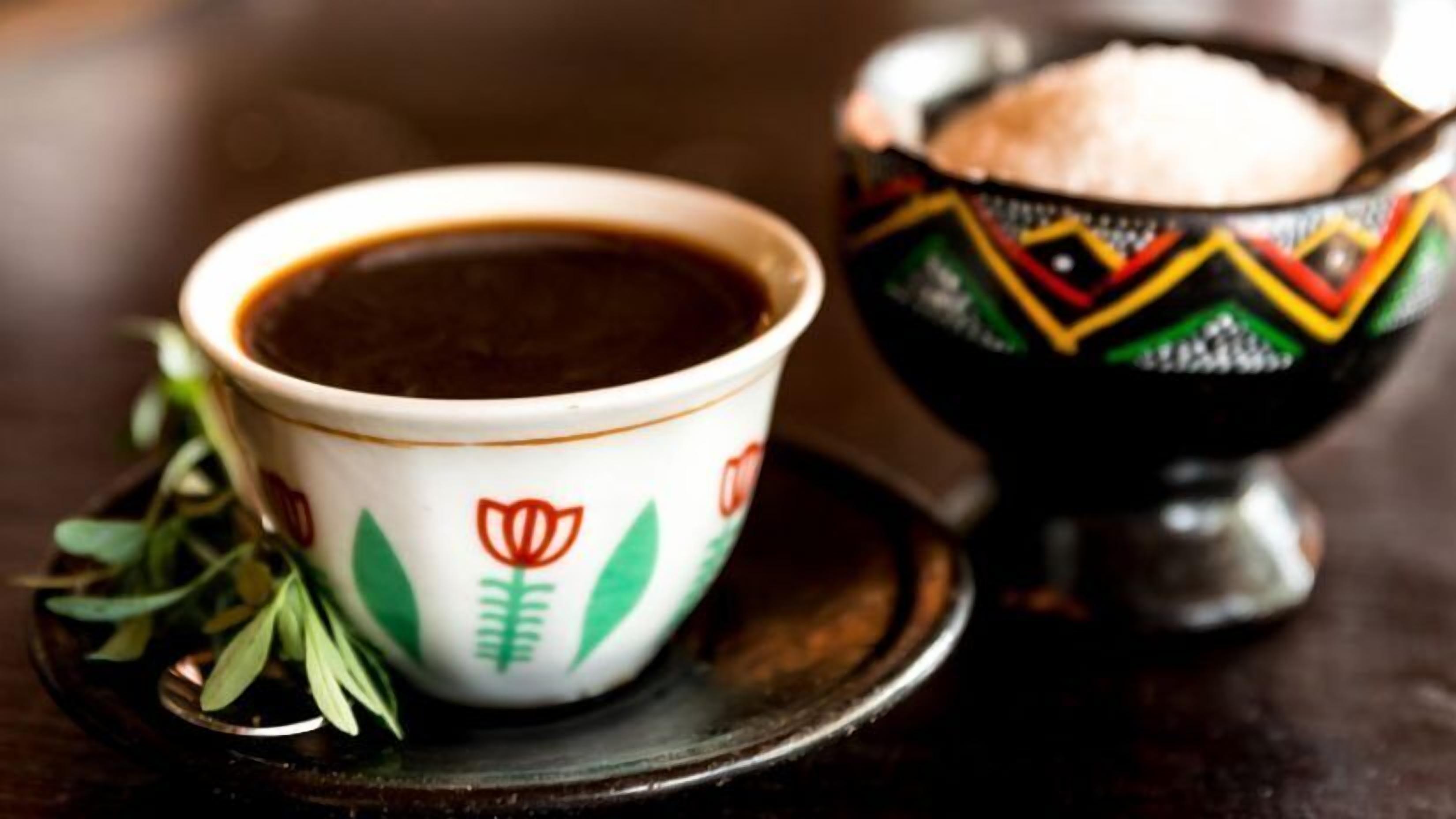 A cup of coffee with a saucer and a decorative bowl.