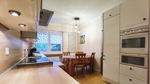Una cocina moderna con encimera de madera, horno empotrado y zona de comedor con mesa y sillas.