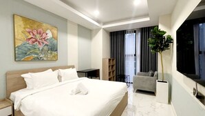 Et moderne hotelværelse med en stor seng, et fjernsyn, en grå sofa og en potteplante.