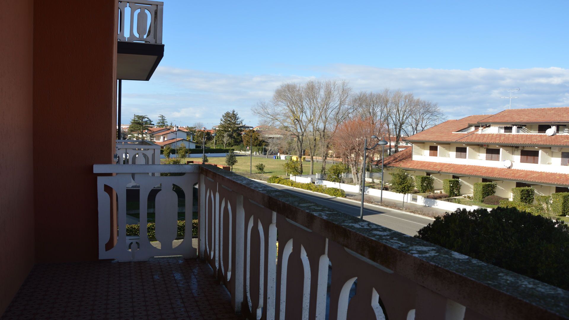 Un balcone con vista su una zona residenziale, tra cui case e una strada.