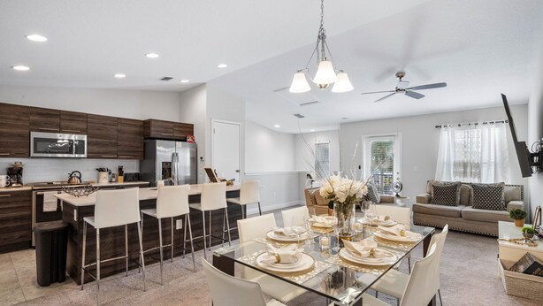A modern kitchen with dark wood cabinets, stainless steel appliances, and a dining area with a glass table set for six.