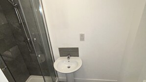 A bathroom with a glass-enclosed shower, a pedestal sink, and a toilet. - Lovely 1-bed Apartment in Salford (Salford)