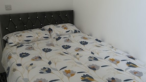 A bed with a floral-patterned duvet and a tufted headboard. - Lovely 1-bed Apartment in Salford (Salford)