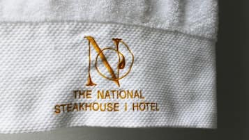 A white towel with embroidered text and a logo reading "THE NATIONAL STEAKHOUSE HOTEL."