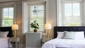 Een hotelkamer met twee bedden, een radiator, een bloempot en twee bedlampjes.