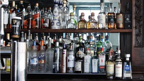 Een bar met planken vol diverse drankflessen.