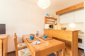 A compact kitchen with wooden furniture, a microwave, and a coffee maker on a shelf. - 100m from resort center, swimming pool, balcony, parking, 28m², Serre Chevalier (SERRE CHEVALIER)