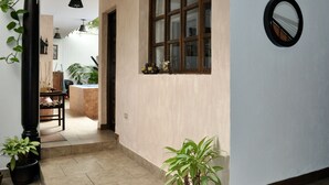 A hallway with a wooden door, a window with a view, and a potted plant.