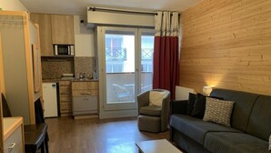A compact living space with a kitchenette, a sofa, a small table, and a chair. - 200m from ski lifts, 2nd floor, balcony, tv, 26m², Brides Les Bains (Brides-les-Bains)