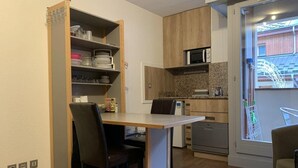 A compact kitchen with a dining area, built-in shelves, and a view of a balcony. - 200m from ski lifts, 2nd floor, balcony, tv, 26m², Brides Les Bains (Brides-les-Bains)