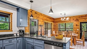 A modern kitchen with grey cabinets, a stainless steel dishwasher, and wooden accents.