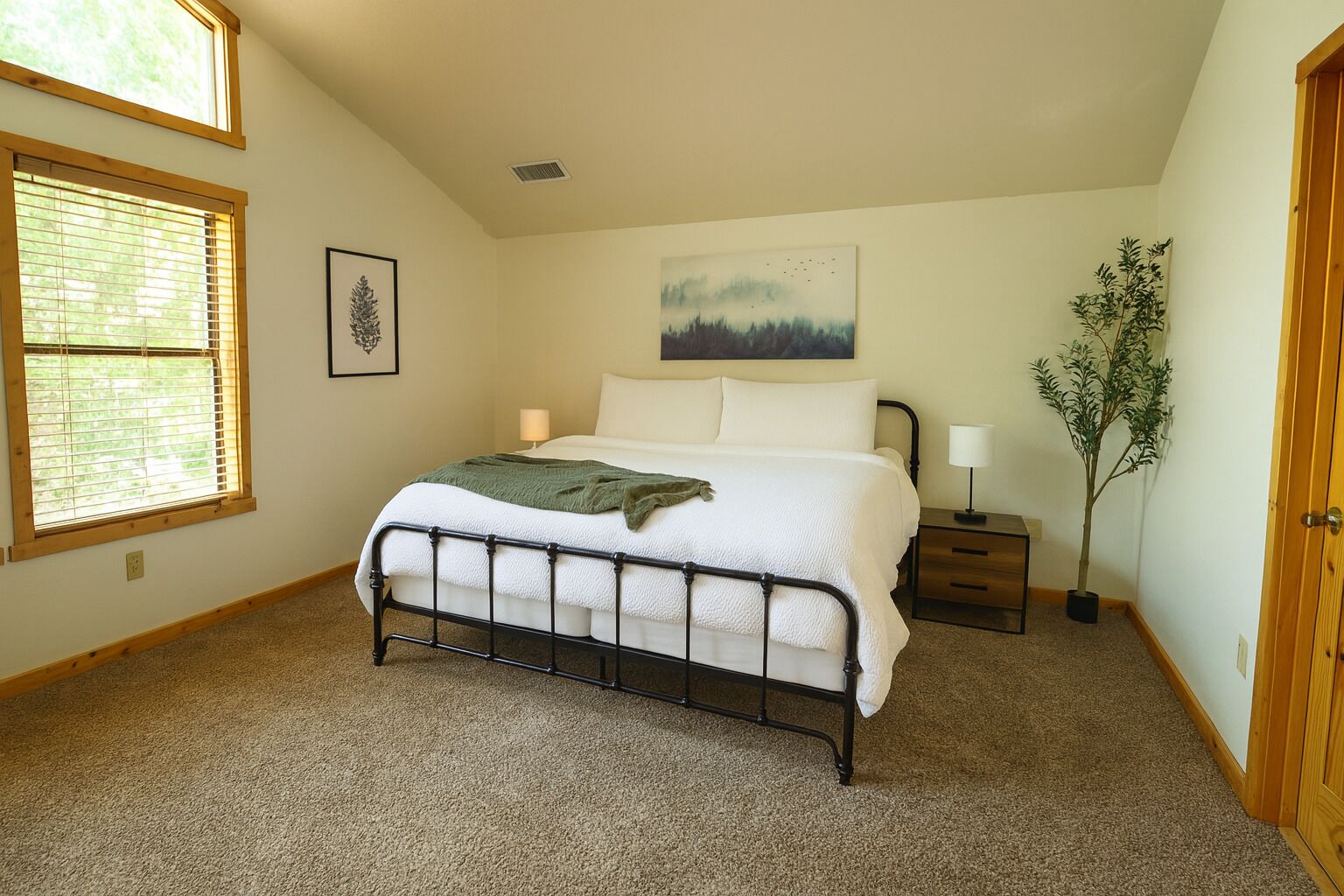 Une chambre à coucher avec un lit, une table de chevet, une lampe, une fenêtre et un tableau au mur.