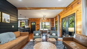 A cozy cabin interior with a wooden interior, a dining area, and a sofa set.