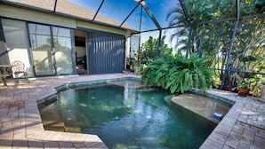 A swimming pool with a brick deck, surrounded by potted plants and a glass door leading to a covered patio area. - Private Guest Suite with Shared Pool Access - just 9 miles from Boca Grande (Port Charlotte)