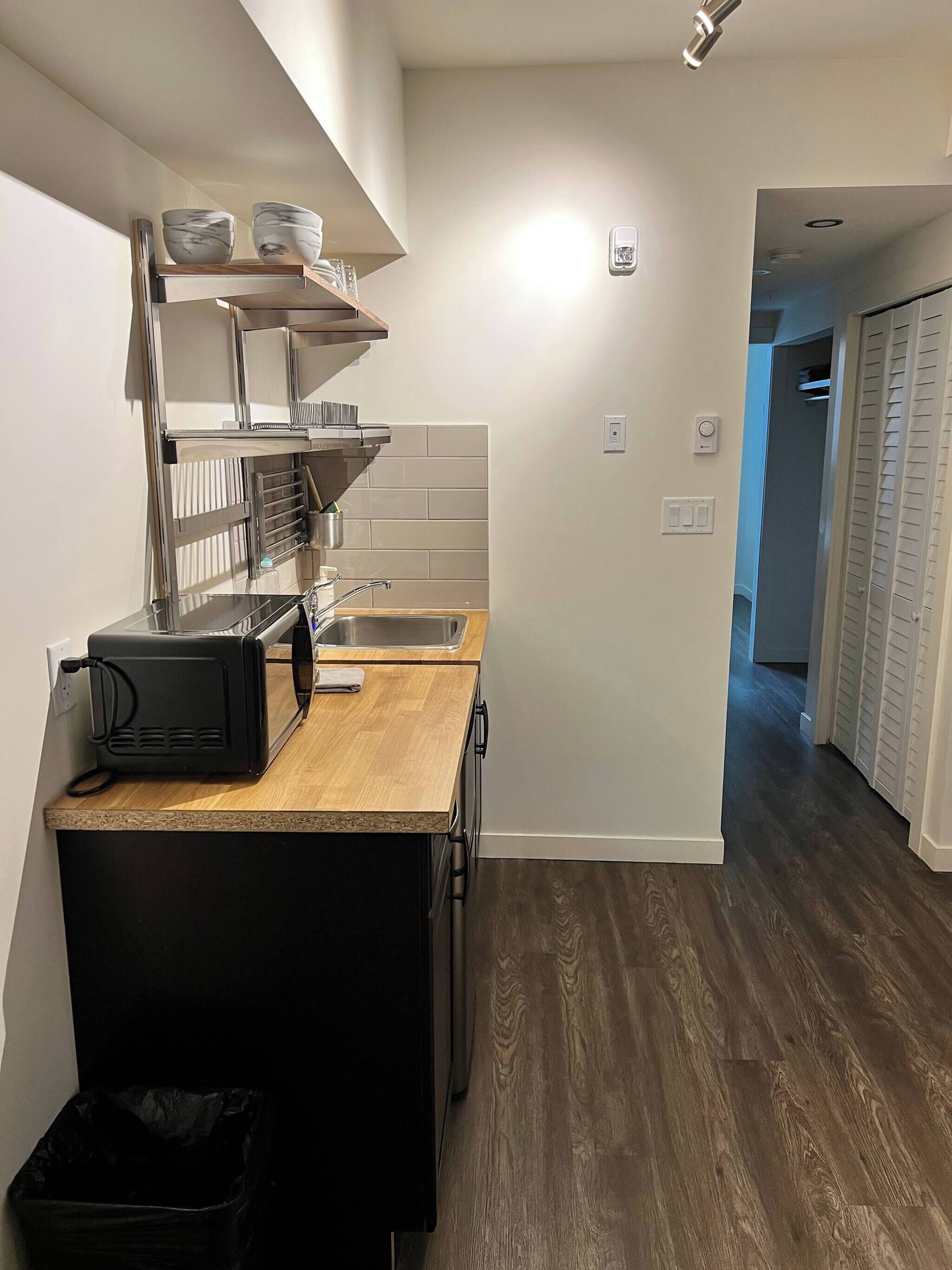 A compact kitchen with a sink, a toaster, and a trash bin.