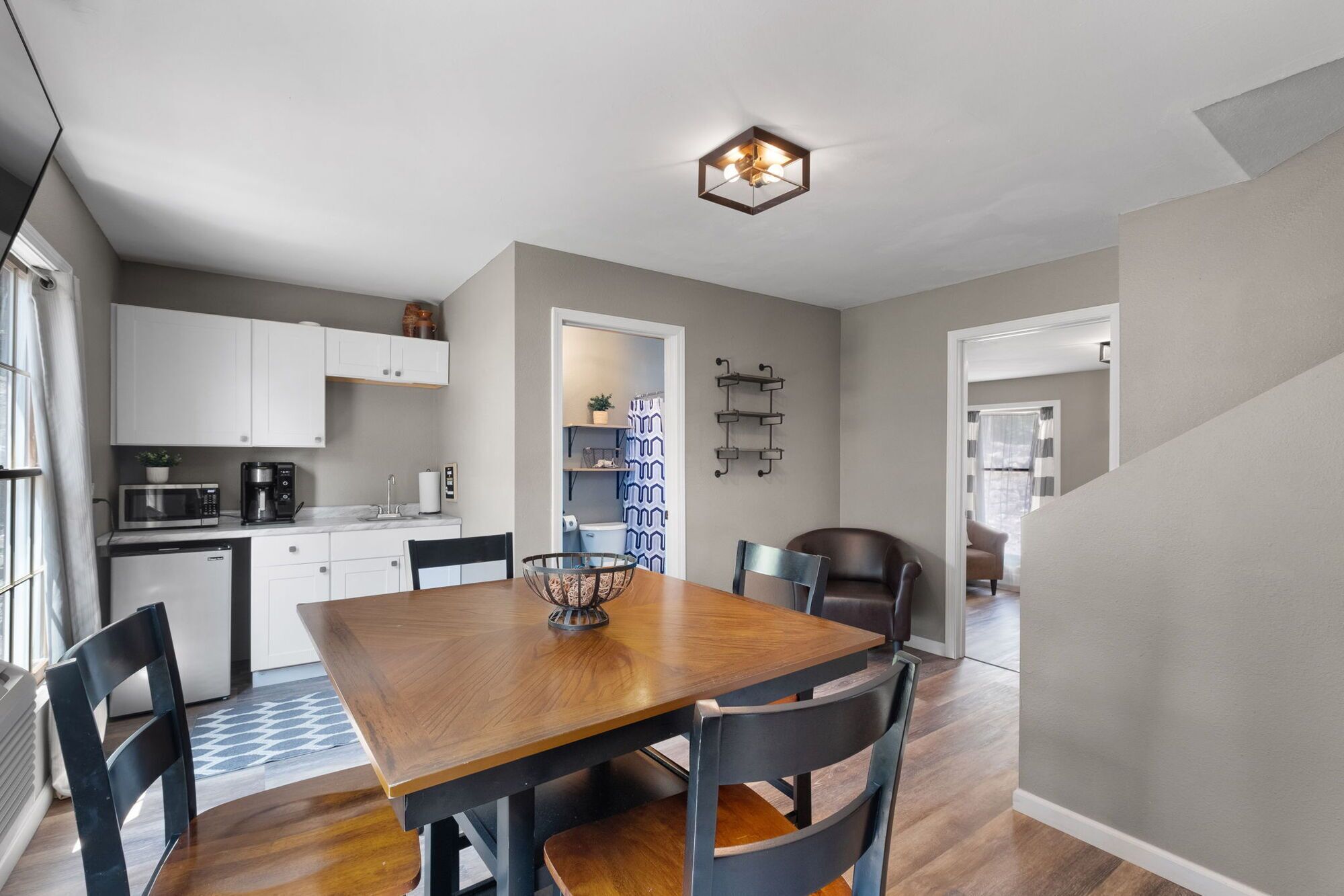 A modern kitchen with white cabinets, a dining table with chairs, and a unique hexagonal ceiling light fixture.