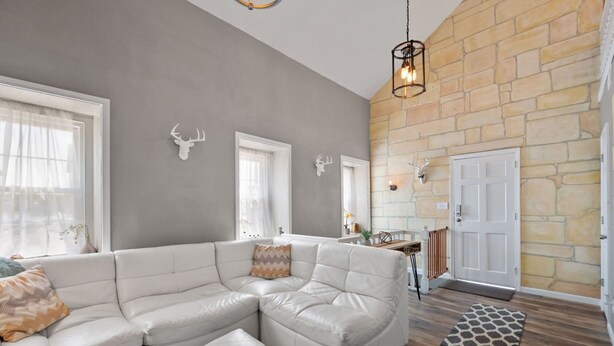 A spacious living room with a large L-shaped sectional sofa, a stone fireplace, and a wooden floor.