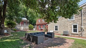 A backyard with a brick patio, outdoor furniture, and a stone building.