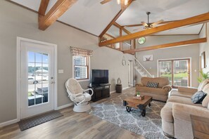 A spacious living room with wooden beams, a television, a sofa, and a coffee table.