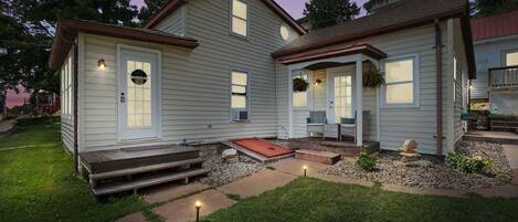 A two-story house with a front porch, a small front yard, and a driveway.