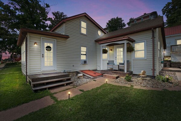 A two-story house with a front porch, a small front yard, and a driveway.