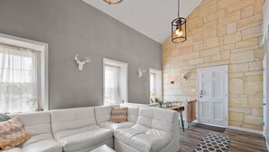 Un salón amplio con un sofá seccional en forma de L, una chimenea de piedra y piso de madera.