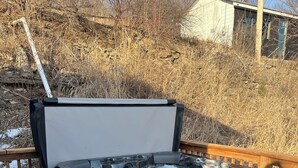 Una banyera d'hidromassatge sobre un balcó de fusta amb barana i un banc de fusta.