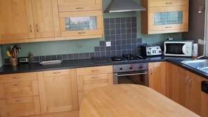 Een moderne keuken met houten kastjes, een gasfornuis, een magnetron en een spoelbak.