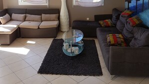 Een woonkamer met twee banken, een salontafel en een groot schilderij van een strand.