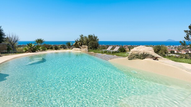 Une piscine aux eaux cristallines, avec vue sur l’océan et une plage de sable fin.