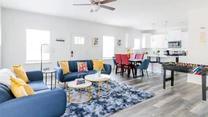 Ein modernes Wohnzimmer mit einem blauen Sofa, zwei Couchtischen und einem Kicker.