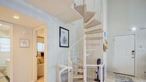 A spiral staircase with a cat tree, a framed picture of a sailboat, and a door with a security device.