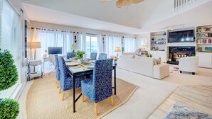 A modern living room with a dining area, a TV, and a fireplace.