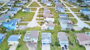An aerial view of a coastal residential area with houses, roads, and a beach.