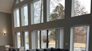 A spacious living room with a large sectional sofa, two coffee tables, and a dining area with a table and chairs. - Amenity loaded golf course retreat! (Marion)