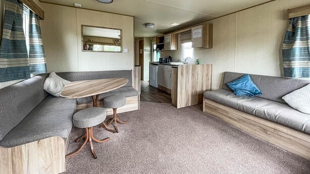 A compact RV interior with a dining area, kitchenette, and seating space. - Caravansleeps8-hottub-fireplace-garden-patio (Lincoln)