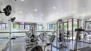 Une salle de sport équipée de divers appareils d’exercice, dotée de grandes fenêtres et d’un intérieur propre et moderne.