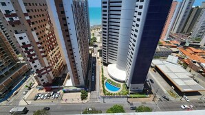 Un immeuble de grande hauteur au design moderne, comprenant de nombreux étages et une cour intérieure avec une piscine.