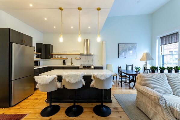 A modern kitchen with a central island, bar stools, and pendant lighting.