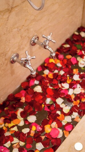 A bathtub filled with rose petals and a faucet.