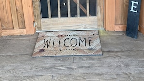 A wooden door with a metal gate, a welcome mat, and a sign that reads "WELCOME". - White Bluff Cabin overlooking Lake Malone  (Lewisburg)
