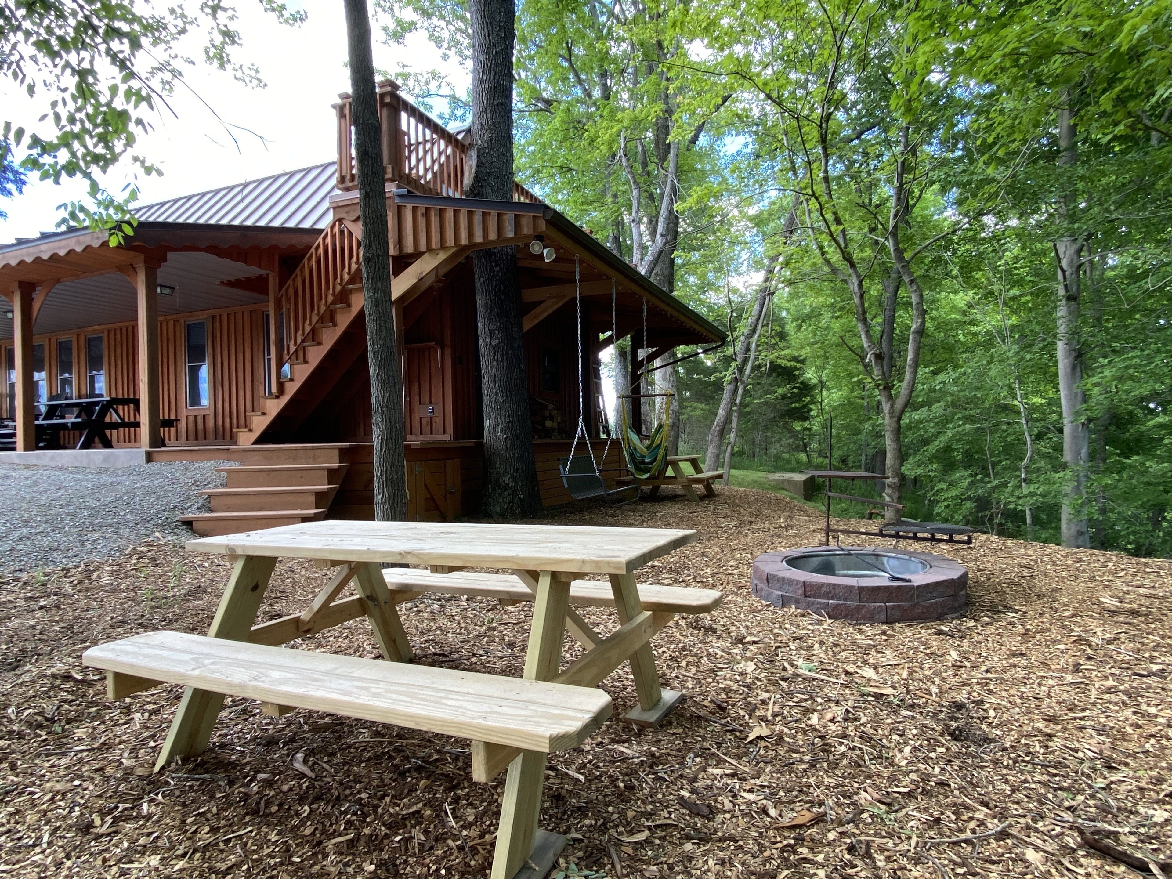 Una cabaña de madera con porche, mesa de picnic y fogón.
