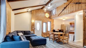 Uma sala de estar espaçosa com sofá modular, banquinho e mesa de jantar com cadeiras.